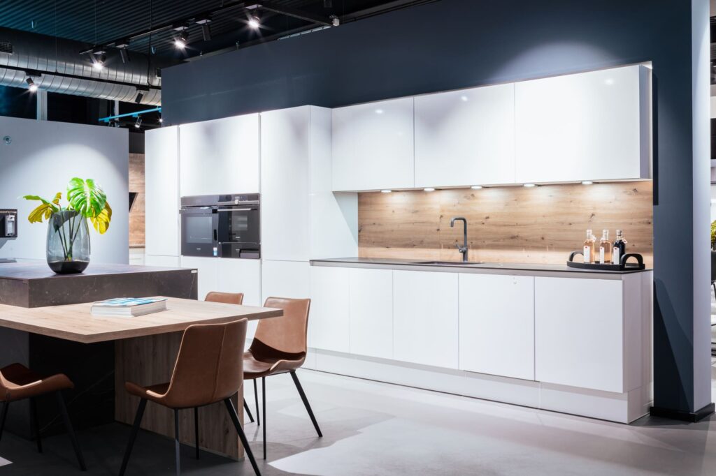 Elegante, weiße Küche mit dunkler Kücheninsel und Holzrückwand